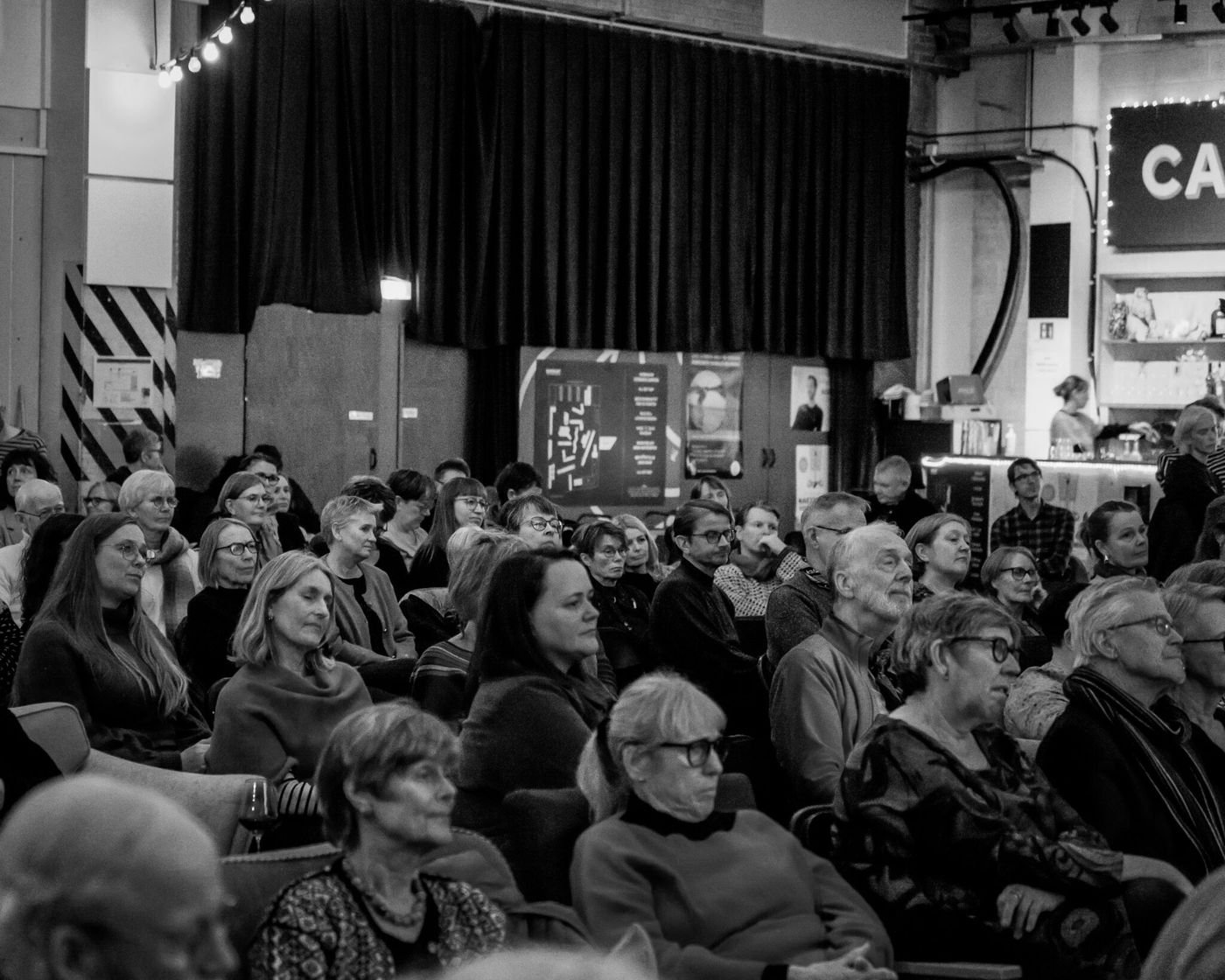 Fullsatt sal som lytter, svart-hvitt